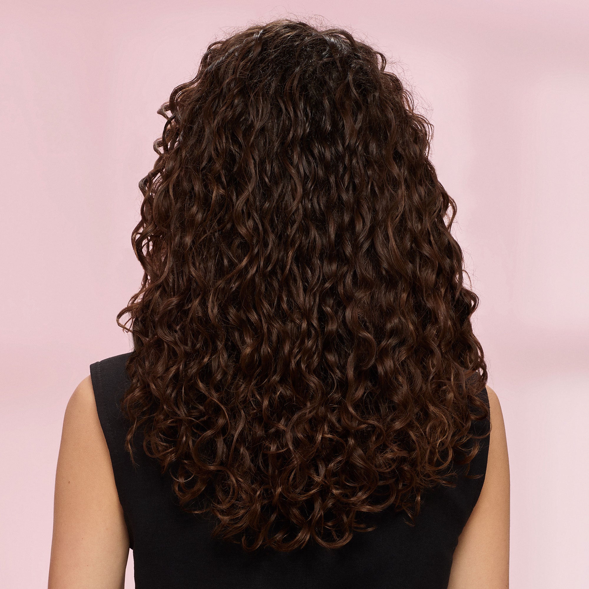Person with long, wavy brown hair on a pink background after using the Diffon Worldwide
